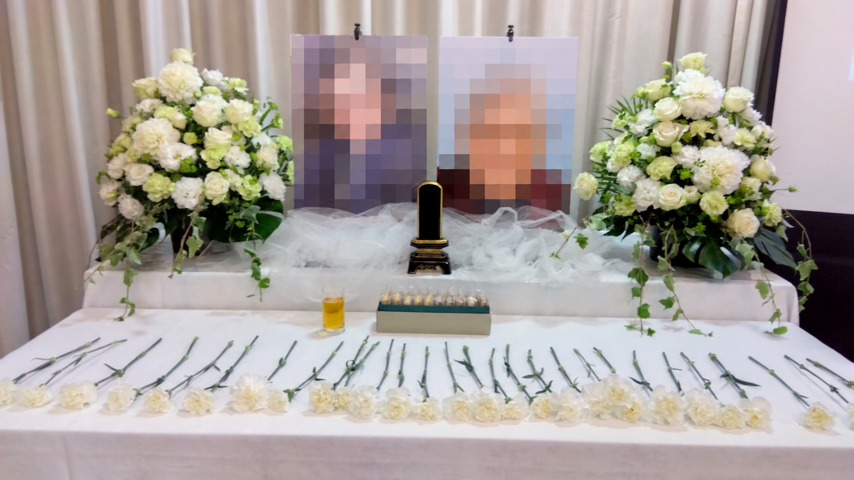二枚の写真と白い花を飾り、献花用の花を並べた恩師を偲ぶ会