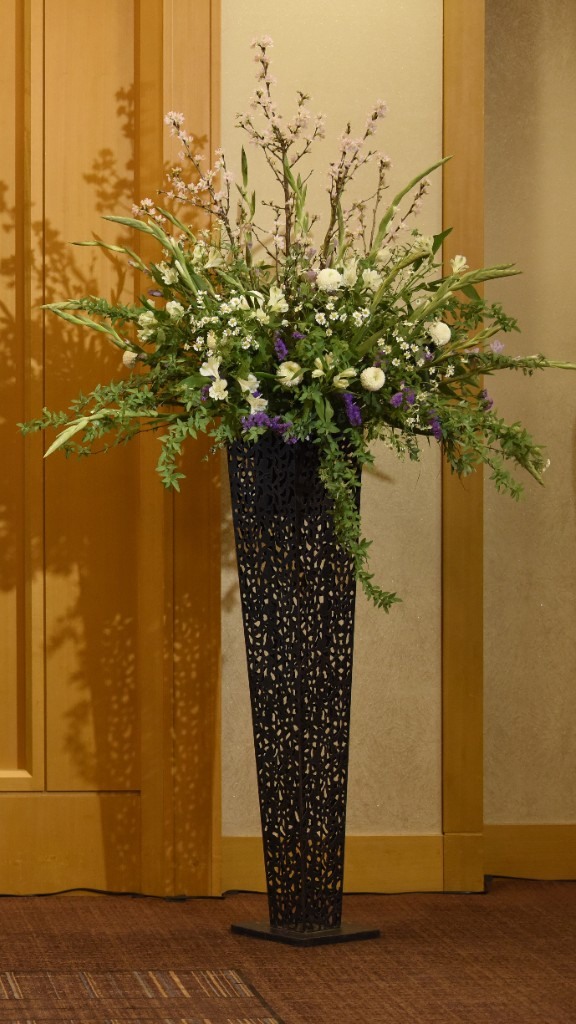 枝ものと白い花を黒い花器に生けた入口の装花